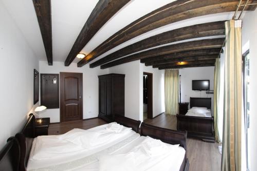 1 dormitorio con 1 cama grande y techo de madera en Pensiunea Rafael en Păltiniş