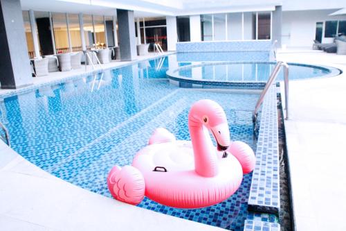 a swimming pool with a pink swan float in the water at Merapi Merbabu Hotels Bekasi in Bekasi