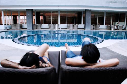 two women laying in chairs in front of a swimming pool at Merapi Merbabu Hotels Bekasi in Bekasi