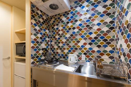 a kitchen with a sink and a mosaic wall at Inari Ohan in Kyoto