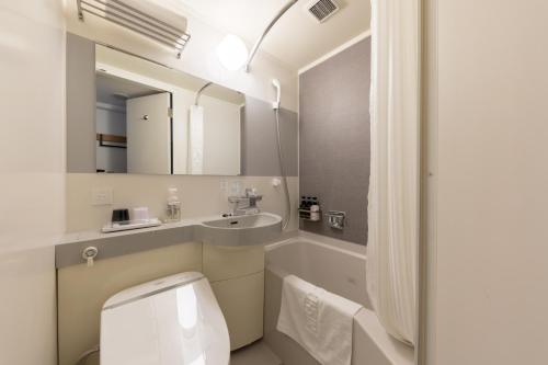 a bathroom with a toilet and a sink and a mirror at Nishitetsu Inn Nihonbashi in Tokyo
