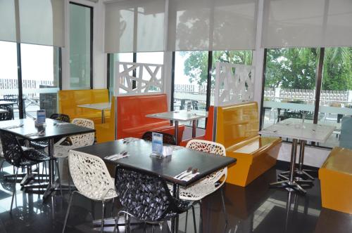 a restaurant with tables and chairs and windows at Klana Beach Resort Port Dickson in Port Dickson