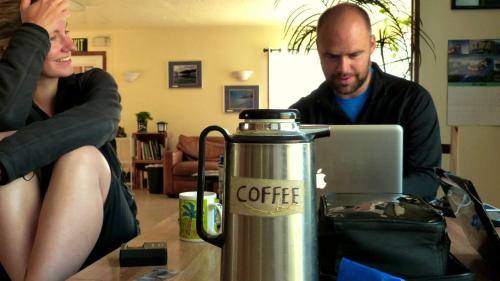 a man and a woman sitting at a table with a coffee machine at Base Camp Anchorage Hostel in Anchorage