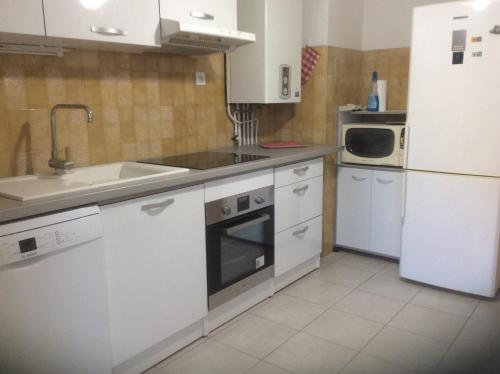 Il comprend une cuisine équipée d'appareils électroménagers blancs et d'un réfrigérateur blanc. dans l'établissement Pietralba Saint Joseph, à Ajaccio