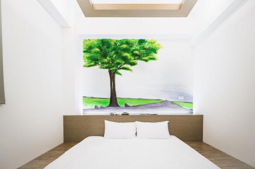 a bedroom with a tree painting on the wall at Tiin Tinn - Rivershore B&B in Taitung City