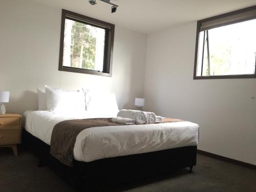 a bedroom with a large bed with two windows at Closeburn LakeView House in Queenstown
