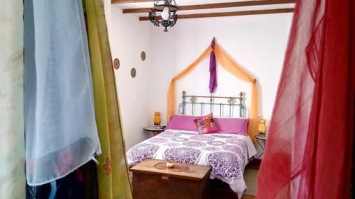 a bedroom with a bed with a canopy and a table at Hotel Rural La Rosa de los Tiempos in Carneros