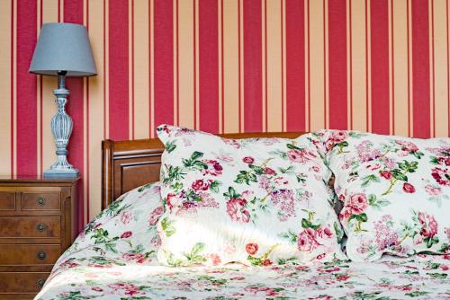 a bed with floral pillows and a lamp on it at La Maison des Palmiers in Homps