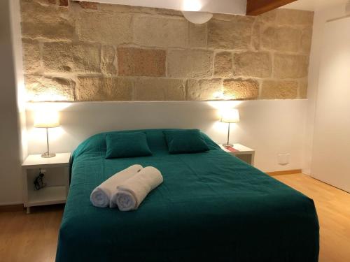 um quarto com uma cama verde com duas toalhas em Hostel Menorca em Ciutadella