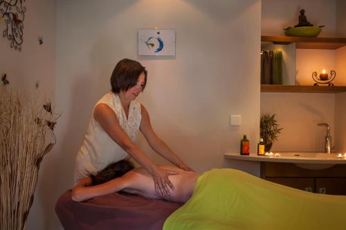 a woman sitting on a bed getting a massage at Logis Hostellerie Motel Au Bois Le Sire in Orbey