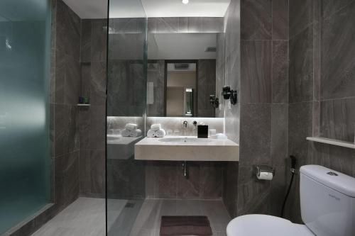 a bathroom with a sink and a glass shower at Aston Banyuwangi Hotel and Conference Center in Banyuwangi