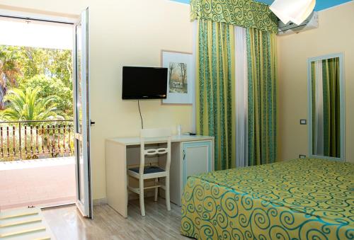 a bedroom with a bed and a desk and a balcony at Hotel Villa Aurora in Latina
