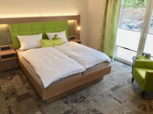 a bedroom with a large bed with a green headboard at Landhotel Witte-König in Garrel