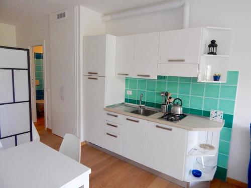 a kitchen with white cabinets and green tiles at S127 - Sirolo, nuovissimo monolocale con terrazzo in Sirolo