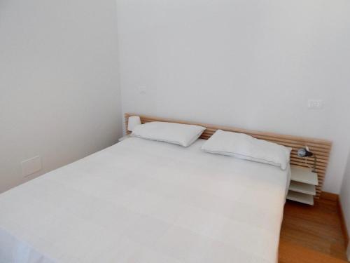 una camera con un letto bianco con due cuscini bianchi di S127 - Sirolo, nuovissimo monolocale con terrazzo a Sirolo