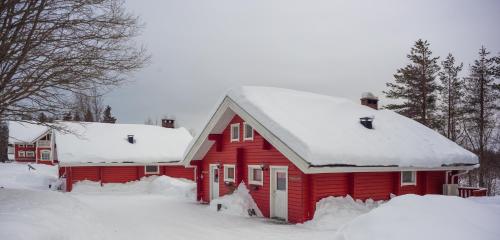 a red house with snow on the roof at Holiday Village Kuukiuru in Vuostimo