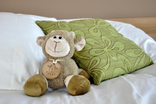 um macaco de peluche sentado numa cama ao lado de uma almofada em Hotel Havenzicht Texel em Oudeschild