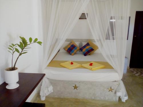 een slaapkamer met een bed met gordijnen en een tafel bij Sleepy Head Guesthouse in Unawatuna