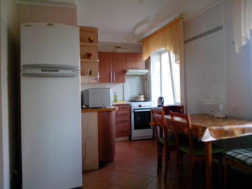 キーウにあるComfortable flat near Dnieper & 12 min. of centreのキッチン(冷蔵庫、テーブル、椅子付)