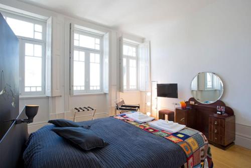 a bedroom with a bed and a mirror and windows at 14º Esquadra — Cais das Pedras Guest House in Porto