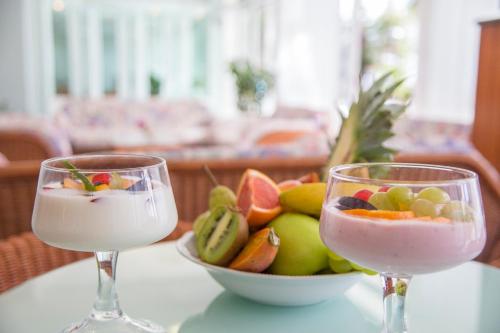 two wine glasses sitting on a table with a bowl of fruit at Rabbit Home in Misano Adriatico
