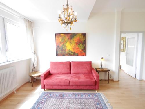 a red couch in a living room with a chandelier at Hotel Rotdorn in Berlin