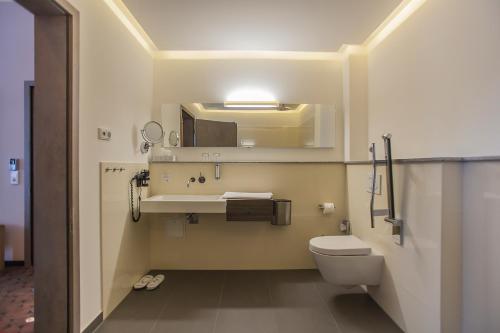 a bathroom with a toilet and a sink and a mirror at AKZENT Hotel Villa Saxer in Goslar
