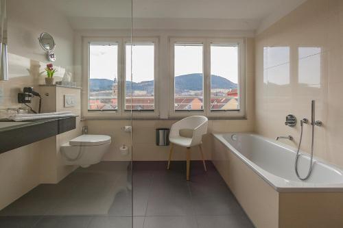 a bathroom with a tub and a toilet and a sink at AKZENT Hotel Villa Saxer in Goslar