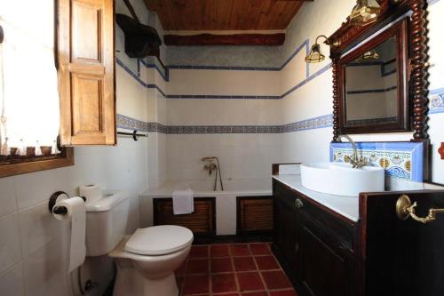 a bathroom with a toilet and a sink and a tub at Hotel Rural La Enhorcadora in Portillo