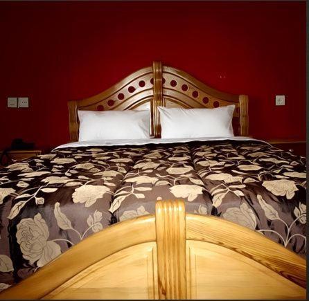 a bedroom with a large bed with a wooden headboard at Hotel Porte Atlas in Imouzzer Kandar