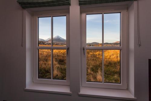 a window with three views of a mountain at Dark Skye Cottage in Broadford