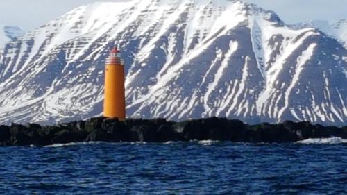 a lighthouse in front of a snow covered mountain at The Viking Country Club in Hjalteyri