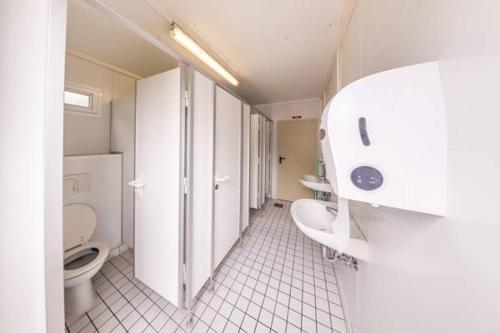 a bathroom with a toilet and two sinks and a toilet paper dispenser at Campingplatz am Hünstein in Nohra