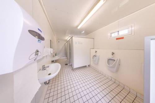 ein Badezimmer mit einem Waschbecken, einem WC und einem Urinal in der Unterkunft Campingplatz am Hünstein in Nohra