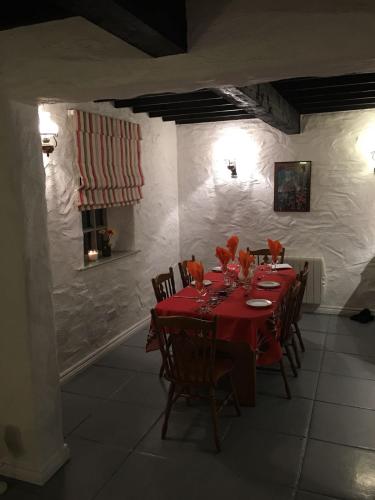 a dining room with a red table and chairs at Dunguaire Thatched Cottages in Galway