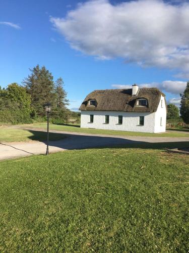 a building with a thatched roof on a field of grass at Dunguaire Thatched Cottages in Galway