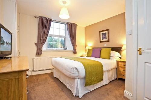 um quarto com uma cama grande e uma janela em The Watermill Inn & Brewery em Windermere
