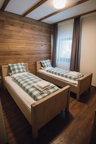 two beds in a room with a window at Madarasi Gyopár Panzió in Izvoare