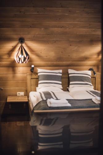 a bed in a room with a wooden wall at Madarasi Gyopár Panzió in Izvoare