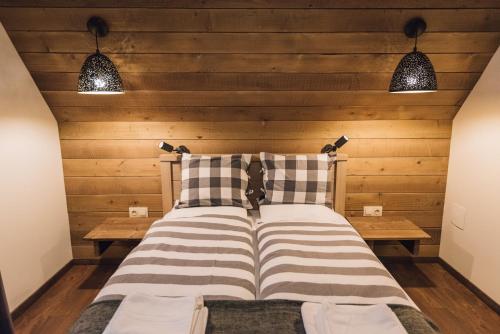 a bed in a room with wooden walls and lights at Madarasi Gyopár Panzió in Izvoare
