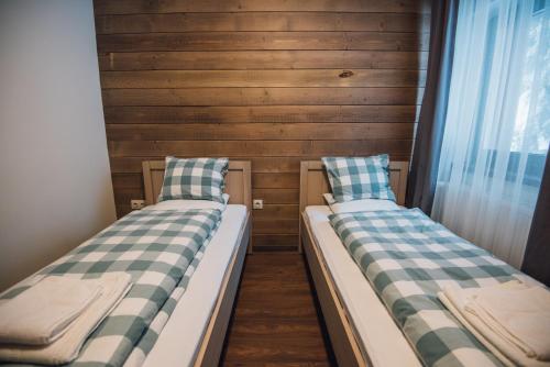 two beds in a room with wooden walls at Madarasi Gyopár Panzió in Izvoare