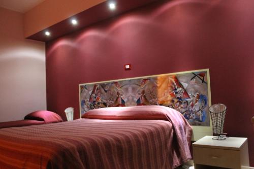 a bedroom with a bed with a painting on the wall at Il Fiore di San Giovanni B&B in Milazzo