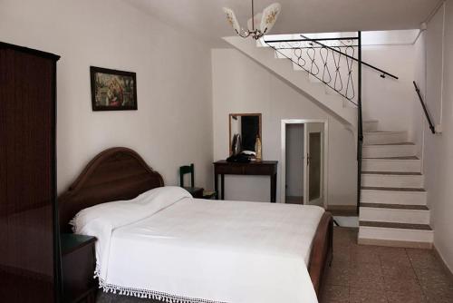 a bedroom with a white bed and a staircase at Casa Allegra e Colorata in Badolato