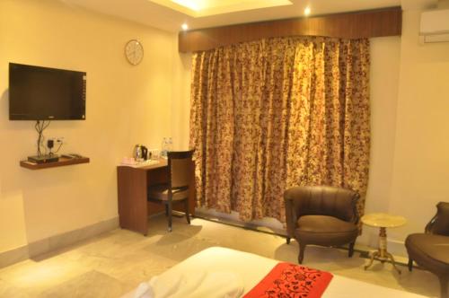 a hotel room with a bed and a desk and a television at Sher-E-Punjab in Kolkata