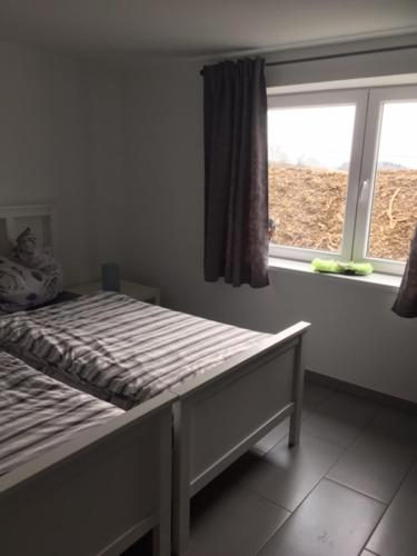 a bed in a room with a window and a bed frame at Ferienwohnung Stricker in Birken-Honigsessen