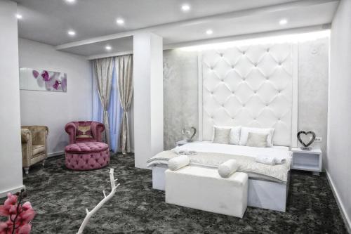 una camera con un letto bianco e una sedia rosa di Sunny Hill Garden a Stara Pazova