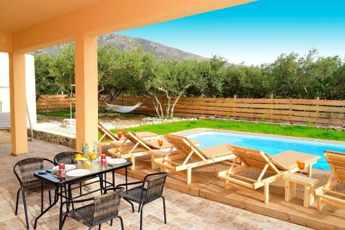 un patio avec une table et des chaises à côté d'une piscine dans l'établissement White Lake Holiday House, à Elafonisi