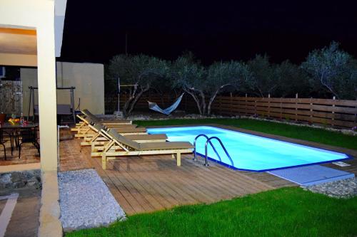 a swimming pool with chairs and a swing at night at White Lake Holiday House in Elafonisi