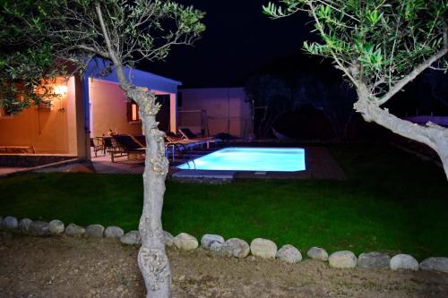 a backyard with a swimming pool at night at White Lake Holiday House in Elafonisi