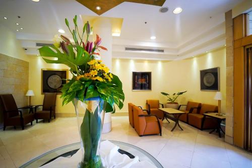 a vase of flowers sitting on a table in a lobby at Ambassador Hotel in Jerusalem